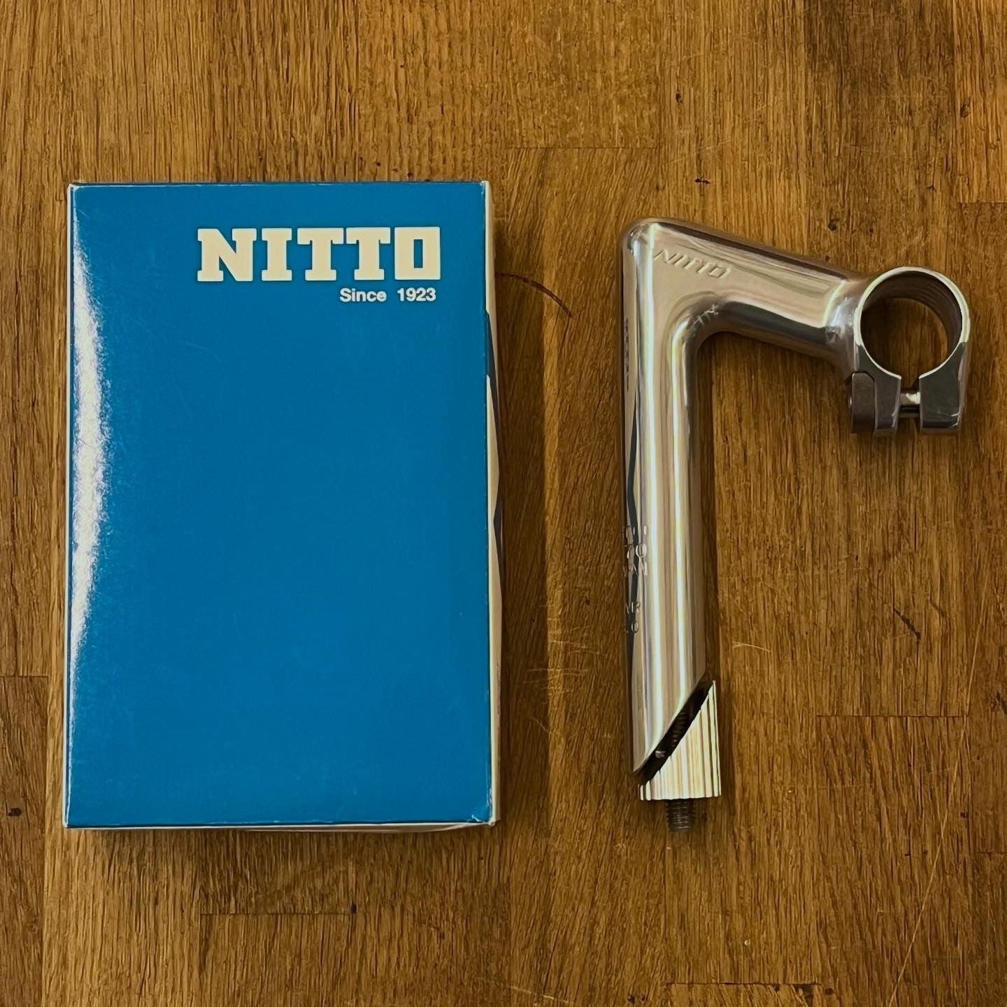 Silver metal component next to a blue Nitto box on a wooden surface
