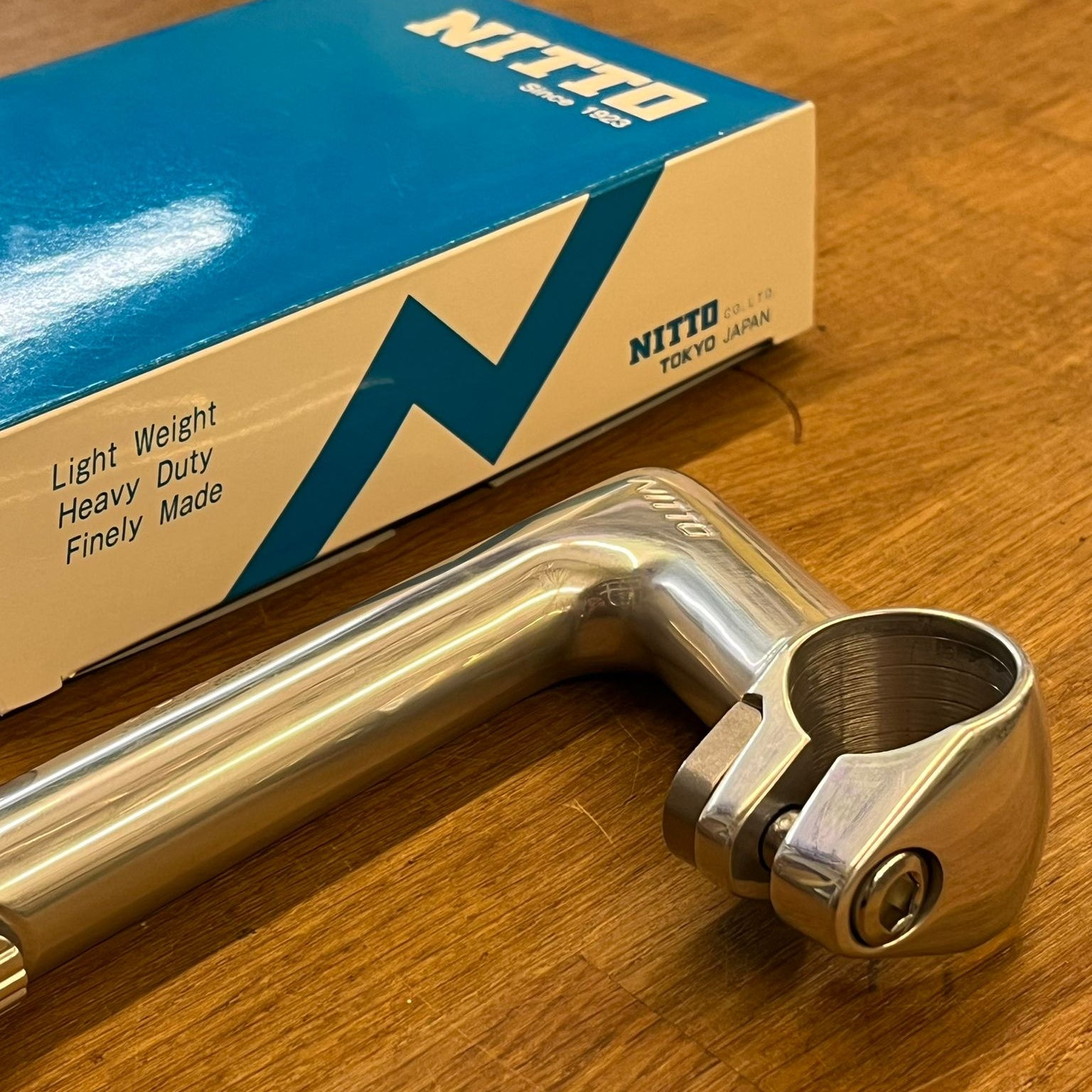Metal handlebar with Nitto packaging on a wooden surface