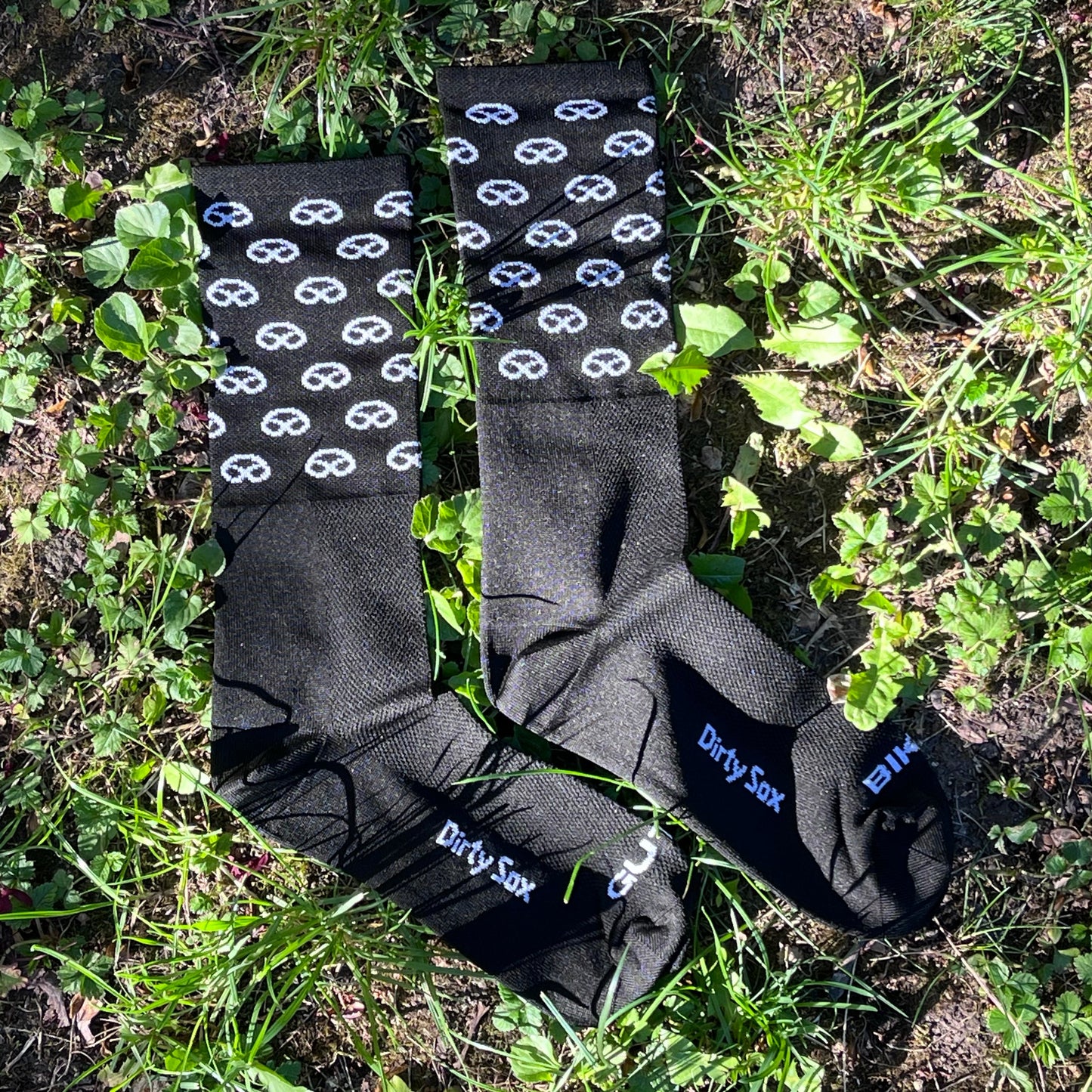 Two pairs of black socks with white patterns on a grassy background
