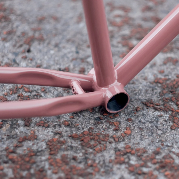 Close-up of a pink bicycle frame on a textured surface