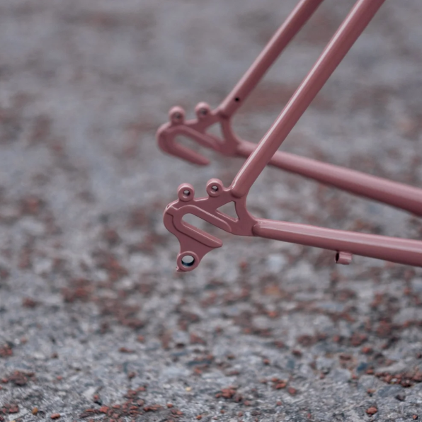 Close-up of a pink bicycle frame on a textured surface