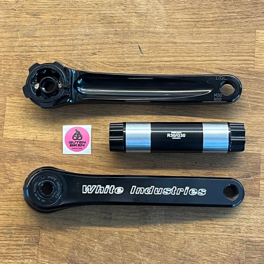 Bicycle crankset components on a wooden surface with a visible brand sticker.