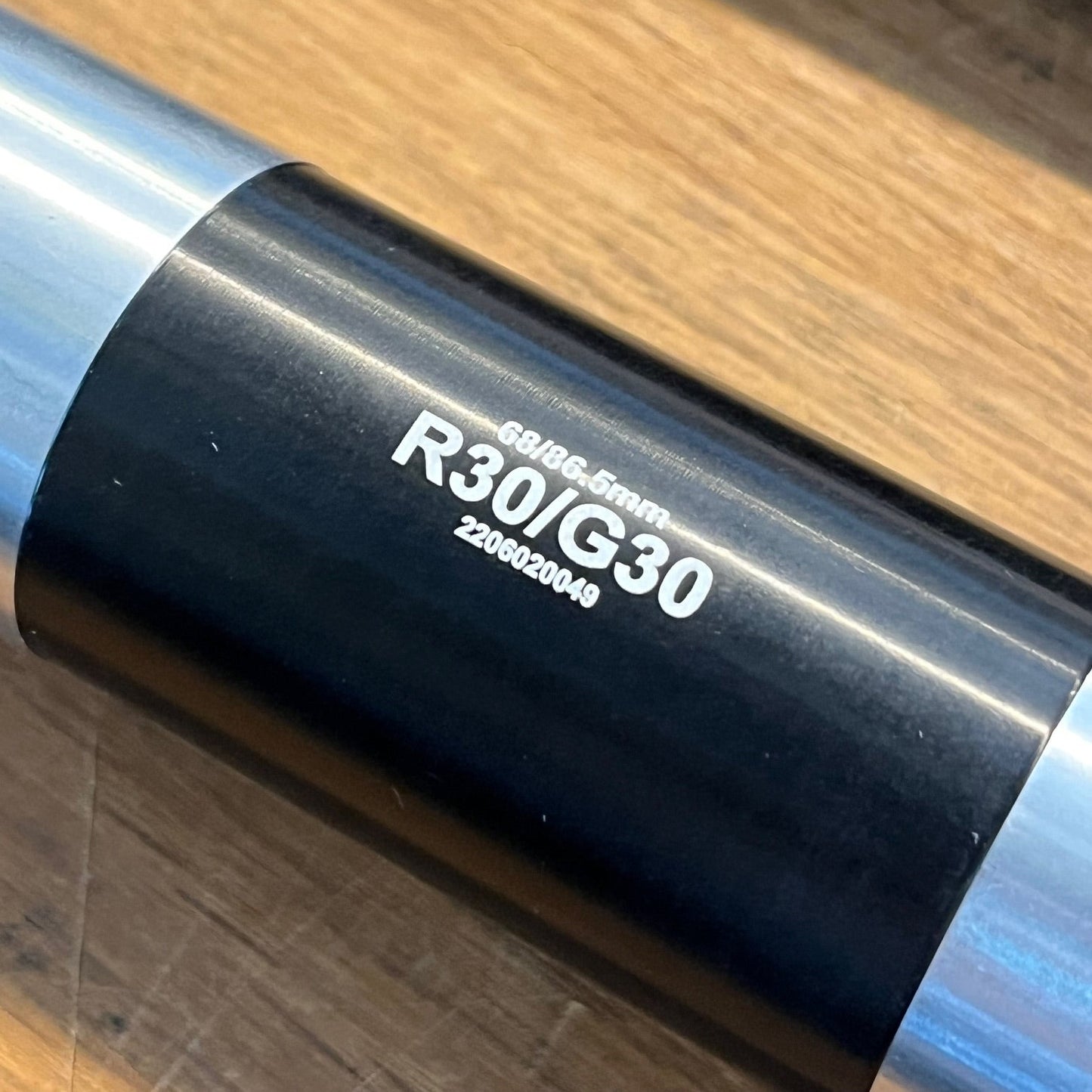 Close-up of a motorcycle exhaust with 'R30IG30' branding on a wooden surface.