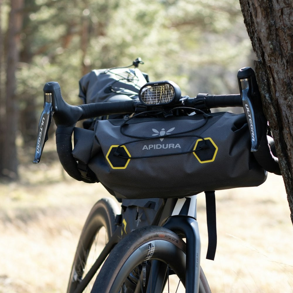 Bicycle with Apidura bag attached to a tree in a forest setting